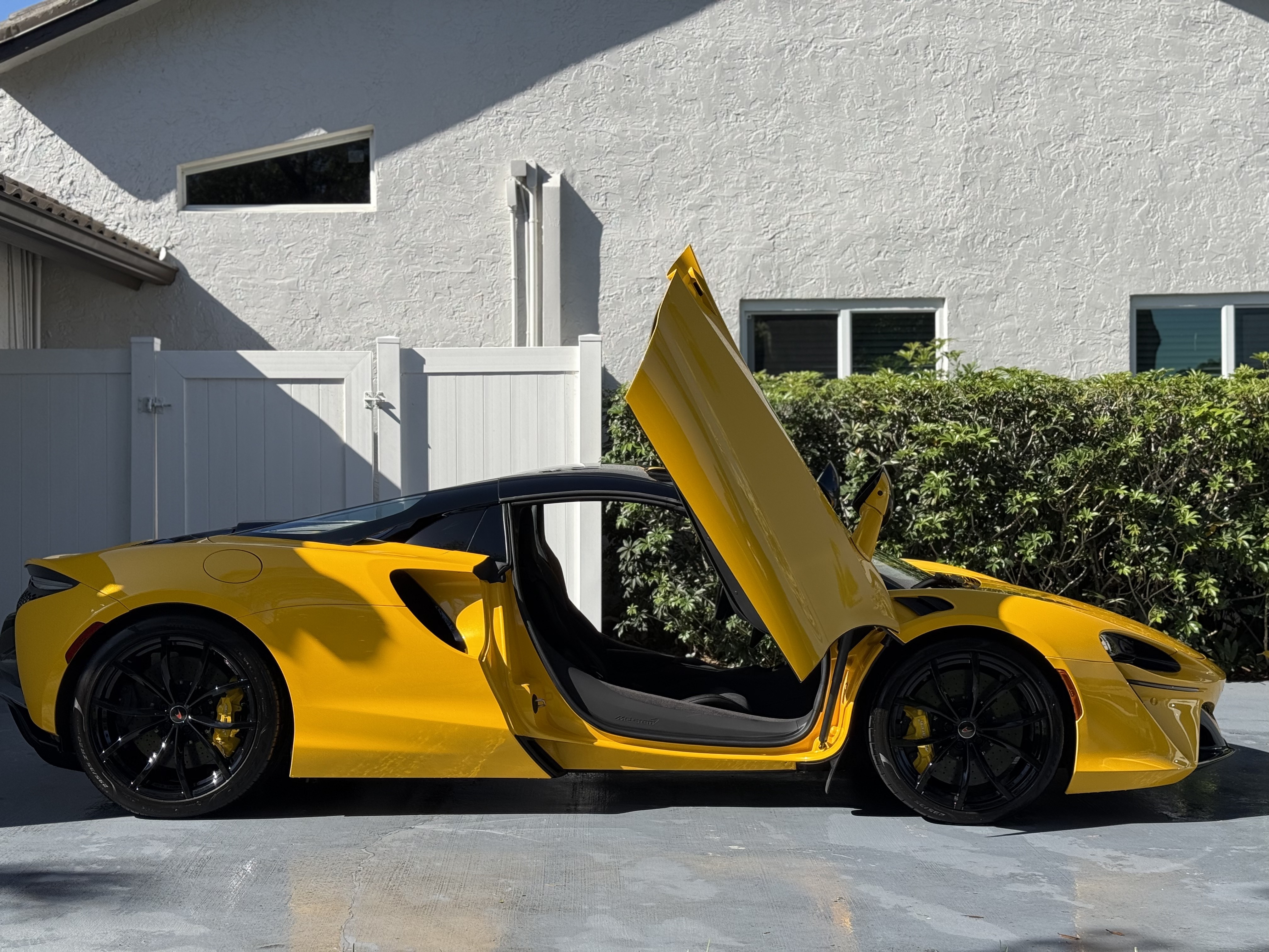 Yellow McLaren Artura with dihedral doors open after a detail